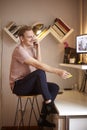 One young man, sitting in bar stool, smiling and talking over phone, at home. desk with computer equipment in front of him Royalty Free Stock Photo