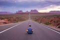 One young man sitting on the highway to monument valley at beautiful purple sunset