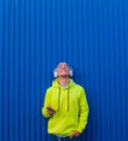 One young man or teenager millennial listening music with his phone and headphones looking up enjoying music and the moment - Royalty Free Stock Photo