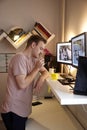 One young man, thinking in his room. looking to write something on a post-it note. in front of a standing desk, and computer Royalty Free Stock Photo