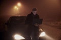 One young man using his laptop computer, on a car hood. It`s dark and night time, in rural area Royalty Free Stock Photo