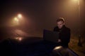 One young man, working using his laptop computer on a car roof, in dark night, rural area Royalty Free Stock Photo