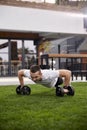 One young man, 20-29 years old, doing push ups with weights in a beautiful backyard of a fancy house