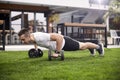 One young man, 20-29 years old, doing push ups with weights in a beautiful backyard of a fancy house