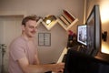 One young man, 20-29 years old, in front of a computer, in his room at home, looking at two monitors attached to a wall Royalty Free Stock Photo