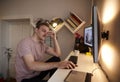 One young man, 20-29 years old, in front of a computer, looking at two monitors attached to a wall. thinking, concentrating