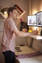 One young man, 20-29 years old, looking to two computer monitors, while working on a computer in his room, at his home. using stan Royalty Free Stock Photo