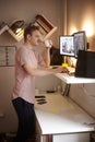 One young man, 20-29 years old, standing at standing desk, working with his computer at his home, in his room Royalty Free Stock Photo