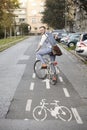 One young man, 20-29 years old, wearing hipster suit, smart casual, looking back to camera, rear view. in city on bike track Royalty Free Stock Photo