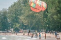 One young men hang on colorful parachute with small girl helping to land after parasailing. Close up photo. Bang Thao beach