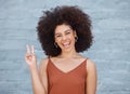 One young mixed race business woman with an afro standing outside against a grey wall and gesturing the peace sign with Royalty Free Stock Photo