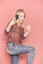 One young rock woman, gesturing with her fingers rock music, while listening it on headphones,