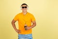 One young smiling handsome asian man in bright summer clothes with headphones isolated over yellow studio background. Royalty Free Stock Photo