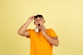 One young smiling handsome asian man in bright summer clothes with headphones isolated over yellow studio background. Royalty Free Stock Photo