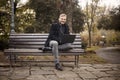 One young smiling and happy man, sitting on bench in public park, using laptop, Royalty Free Stock Photo