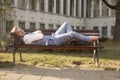 One young smiling man, 20-29 years old, wearing hipster retro suit, laying on bench in park