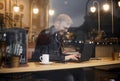 One young smiling man, 20-29 years, sitting in coffee shop and using, typing on keyboard of his laptop. Shoot thought window Royalty Free Stock Photo