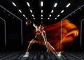 One young sportsman basketball player training in gym, idoors isolated on dark background in mixed light. Concept of Royalty Free Stock Photo