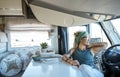 One young traveler woman enjoy time and relax inside modern camper van . Vanlifer smile sitting on driver seat looking outside at Royalty Free Stock Photo