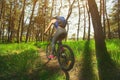 One young woman - an athlete in a helmet riding a mountain bike outside the city, on the road in a pine forest