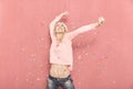 One young woman happy with arms outstreched high in air with confetti thrown, 20-29 years old, long blond hair. Royalty Free Stock Photo