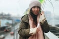 One young woman hiding under umbrella in the sudden heavy and windy spring rain in the city.