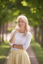 one young woman portrait, 25 years old, yellow dress, white top, park trees behind out of focus, smiling happy