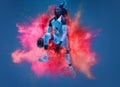 One young woman sportsman basketball player in explosion of colored neon powder isolated on dark blue background