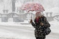 One young woman walking under umbrella in heavy snowfall in city street by the park Royalty Free Stock Photo