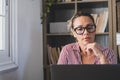 One young woman working at home in the office with laptop and notebook taking notes talking in a video conference. One Royalty Free Stock Photo