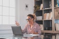 One young woman working at home in the office with laptop and notebook taking notes talking in a video conference. One Royalty Free Stock Photo