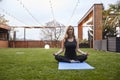 One young woman,20-29 years old, doing yoga while sitting in a sukhasana pose in a beautiful backyard, Royalty Free Stock Photo