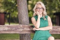 One young woman, 25 years old, sitting in wood bench in park, green dress, happy positive portrait