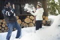 One youthful happy mature couple have fun together playing with snowball in snow winter holiday vacation outside a wooden chalet