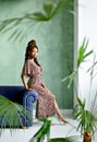 Confident young African lady, wearing dress with leopard print, sitting on the arm of the sofa and looking at the camera Royalty Free Stock Photo