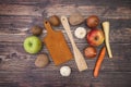 Onion carrot apples and potato with cutting board on wooden table