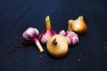 Onion, garlic, colored pepper peas on black wooden background Royalty Free Stock Photo