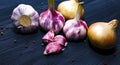 Onion, garlic, colored pepper peas on black wooden background Royalty Free Stock Photo