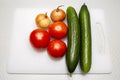 Onion heads, fresh tomatoes and cucumbers on cutting board