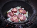 Onions and fresh beef meat cooking over wood fire in cast iron pot or potjiekos, Botswana, Southern Africa