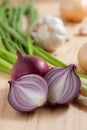 Onions, garlic and spring onions on wooden kitchen