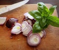 Onions slices and basil on the chopping board Royalty Free Stock Photo