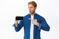 Online advertising, technology concept. Amazed young man pointing and looking at horizontal smartphone screen, showing