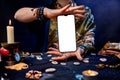 Online astrology. The fortune teller is holding a smartphone with a white screen. Mock up. Close-up. The concept of divination,