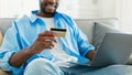 Online banking concept. African american man with laptop and credit card sitting on sofa, purchasing online in webstore Royalty Free Stock Photo