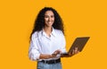 Online Business. Happy Young Woman Holding Laptop Computer And Smiling, Yellow Background Royalty Free Stock Photo