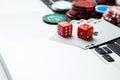 Online casino laptop. Laptop keyboard and chips with dice and playing cards on a green gaming table. Game addiction gambling Royalty Free Stock Photo