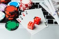 Online casino laptop. Laptop keyboard and chips with dice and playing cards and money cash dollars on green gaming table Royalty Free Stock Photo