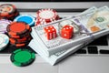 Online casino laptop. Laptop keyboard and chips with dice and money cash dollars on green gaming table. Game addiction gambling