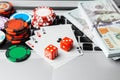 Online casino laptop. Laptop keyboard and chips with dice and playing cards and money cash dollars on green gaming table Royalty Free Stock Photo